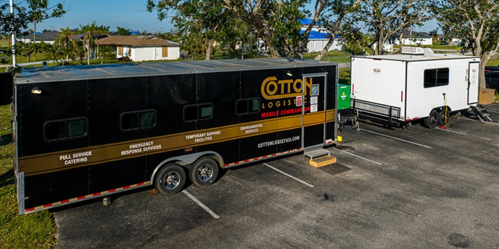 Cotton Logistics mobile command trailer parked in a lot alongside a white support trailer.