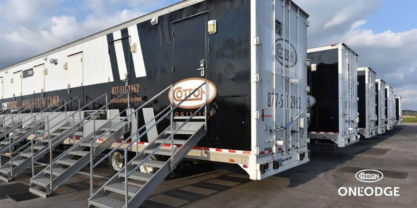 Row of OneLodge mobile crew camp sleeper trailers with steel entry stairs on an asphalt site pad